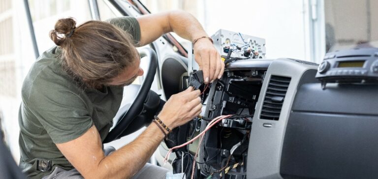 Mann arbeitet an der Elektronik in der Mittelkonsole eines Wohnmobils